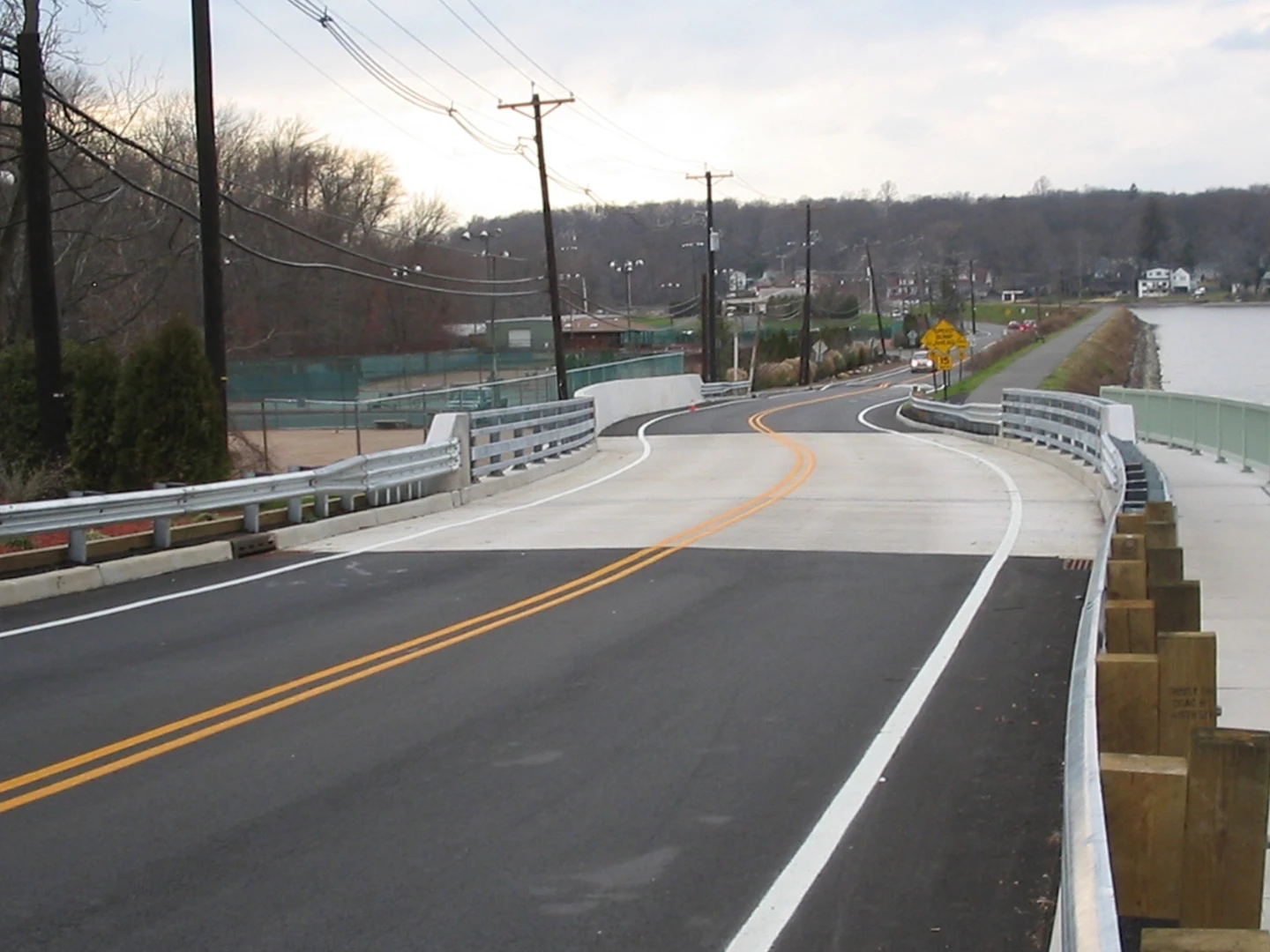 A road with some white fence and a bridge