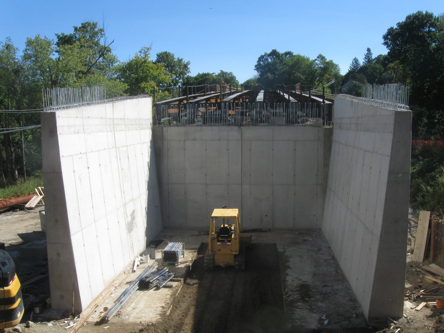 A construction site with concrete walls and trees in the background.