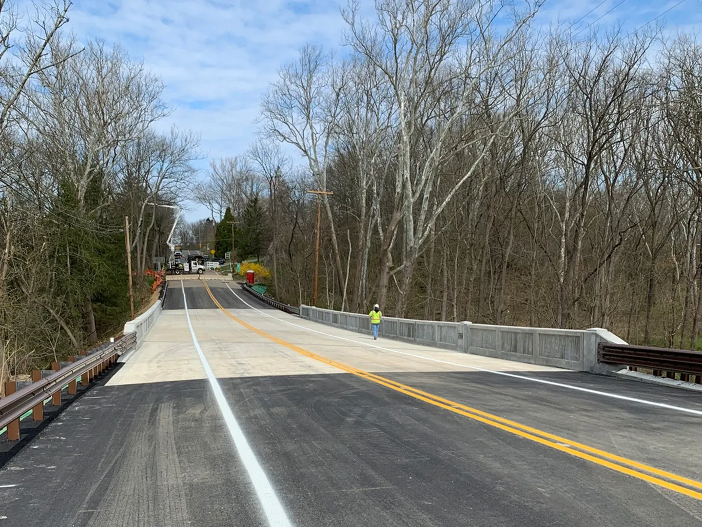 A road with trees and a bridge in the background.